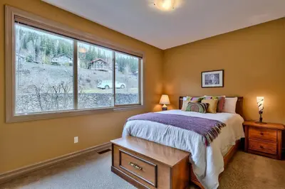 a bedroom with a bed and a large window at Soleil Chalet By Bear Country in Sun Peaks