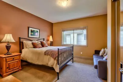 a bedroom with a bed and a window and a couch at Soleil Chalet By Bear Country in Sun Peaks