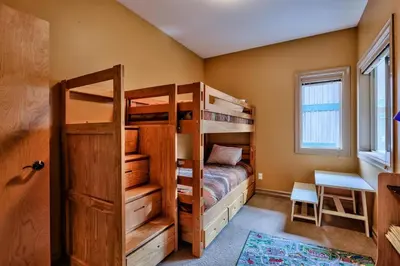 a bedroom with two bunk beds and a desk at Soleil Chalet By Bear Country in Sun Peaks
