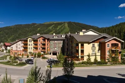 a large apartment complex with a mountain in the background at Fireside Lodge #409 By Bear Country in Sun Peaks