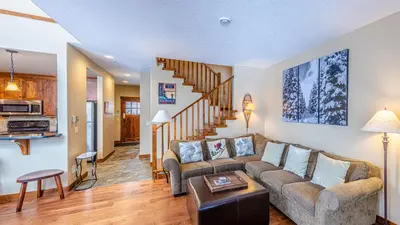 a living room with a couch and a staircase at Woodhaven #36 By Bear Country in Sun Peaks