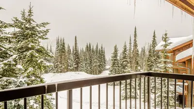 a balcony of a house with snow covered trees at Woodhaven #36 By Bear Country in Sun Peaks