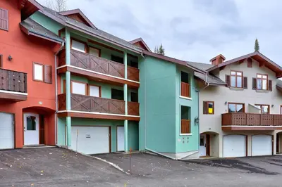 a colorful apartment building with a parking lot at Snow Creek Village #37 By Bear Country in Sun Peaks