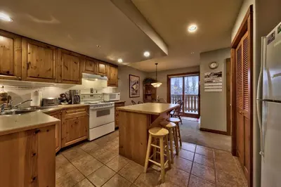 a kitchen with wooden cabinets and a counter top at Timberline Village #14 By Bear Country in Sun Peaks