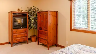 a bedroom with a tv and a wooden cabinet at Timberline Village #38 By Bear Country in Sun Peaks