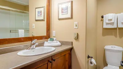 a bathroom with a sink and a toilet and a mirror at Woodhaven #32 By Bear Country in Sun Peaks