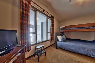 a bedroom with a bed and a flat screen tv at Stones Throw #56 By Bear Country in Sun Peaks