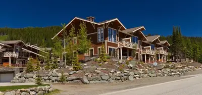 a large wooden house on a hill with trees at Stones Throw #38 By Bear Country in Sun Peaks