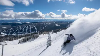 a man riding a snowboard down a snow covered slope at Trappers Landing #27 By Bear Country in Sun Peaks