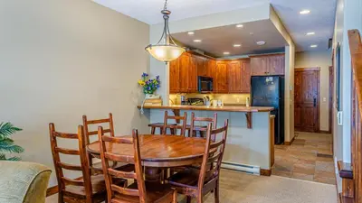 a kitchen and dining room with a wooden table and chairs at Trappers Landing #06 By Bear Country in Sun Peaks