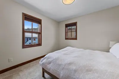 a white bedroom with a bed and two windows at Trappers Landing #05 By Bear Country in Sun Peaks