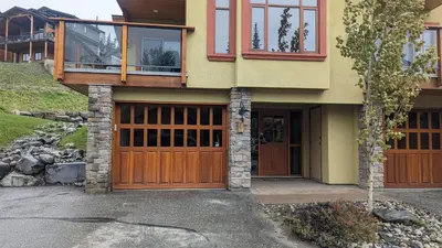a house with wooden garage doors and windows at Trails Edge #03 By Bear Country in Sun Peaks
