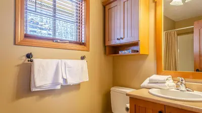 a bathroom with a sink and a toilet and a mirror at Trails Edge #03 By Bear Country in Sun Peaks