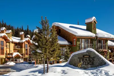 a hotel in the snow with a sign in front of it at Trails Edge #25 By Bear Country in Sun Peaks