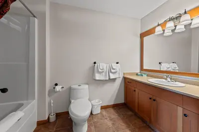 a bathroom with a toilet and a sink and a mirror at Trails Edge #17 By Bear Country in Sun Peaks