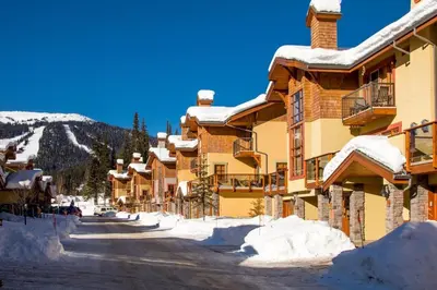 a snow covered street in front of a lodge at Trails Edge #17 By Bear Country in Sun Peaks