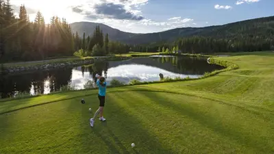 a woman is playing golf on a golf course at Crystal Forest #60 By Bear Country in Sun Peaks