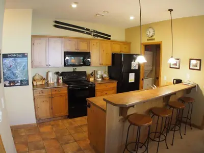 a kitchen with wooden cabinets and a counter with bar stools at Crystal Forest #53 By Bear Country in Sun Peaks