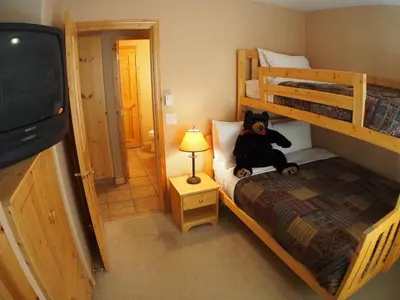 a teddy bear sitting on a bed in a bedroom at Crystal Forest #07 By Bear Country in Sun Peaks