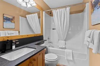 a bathroom with a sink and a tub and a toilet at Crystal Forest #22 By Bear Country in Sun Peaks