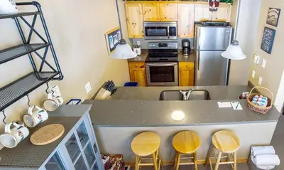 a kitchen with a counter and some yellow cabinets at Crystal Forest #22 By Bear Country in Sun Peaks