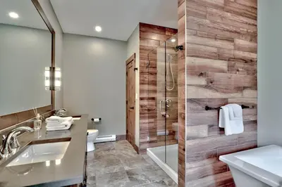 a bathroom with a shower and a sink and a mirror at Village Walk #21 By Bear Country in Sun Peaks