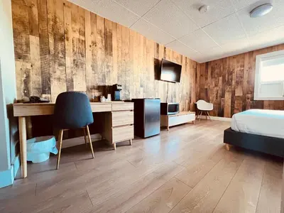 a bedroom with a bed and a desk with a computer at Camrose Le Chateau Hotel in Camrose