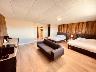 a living room with two beds and a couch at Camrose Le Chateau Hotel in Camrose