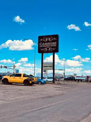 a yellow truck parked next to a sign in a parking lot at Camrose Le Chateau Hotel in Camrose