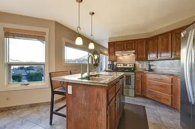 a kitchen with wooden cabinets and a sink at Rodee Homestay in West Kelowna