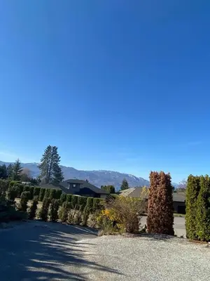 a driveway with hedges and a house in the background at Rodee Homestay in West Kelowna