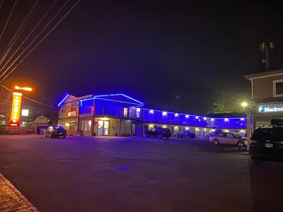 a building with blue lights in a parking lot at night at Imperial Motel in One Hundred Mile House