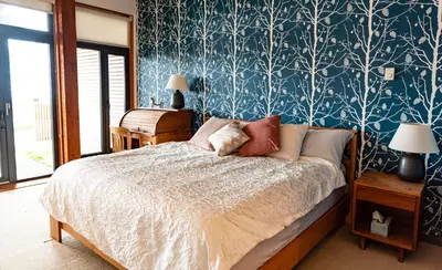 a bedroom with a bed with a blue and white wallpaper at Pacific Soul Eco-Luxe Vacation Home in Ucluelet