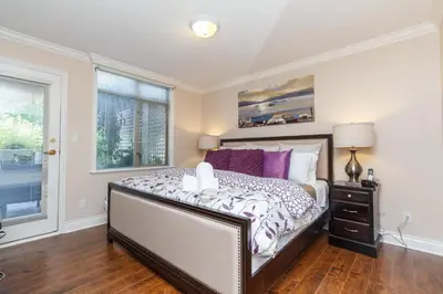a bedroom with a bed with purple pillows and a window at 5 Min Walk To Famous Victoria Inner Harbour And Empress Hotel in Victoria