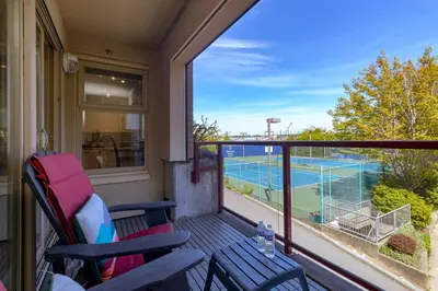 a balcony with two chairs and a tennis court at Deluxe 2 Bed 2 Bath And 5 Min Walk To Downtown And Seawalk in Victoria