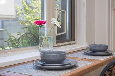 a table with two blue bowls and a vase with flowers at Deluxe 2 Bed 2 Bath And 5 Min Walk To Downtown And Seawalk in Victoria