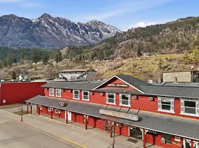 a red building with mountains in the background at Lillooet Hotel Victoria in Lillooet