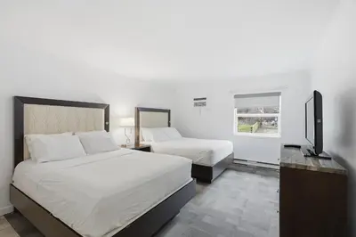 a bedroom with two beds and a flat screen tv at Lillooet Hotel Victoria in Lillooet