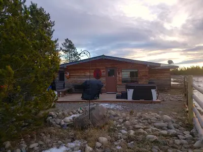 a log cabin with a porch and a grill at Woodhouse Cottages And Ranch in Prince George