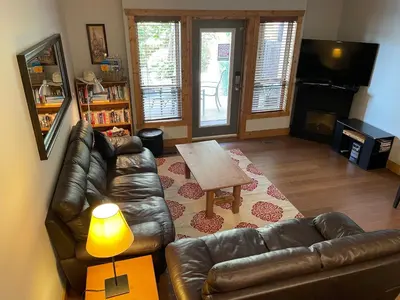 a living room with a leather couch and a table at Casa Del Mila Oro Condo in Osoyoos