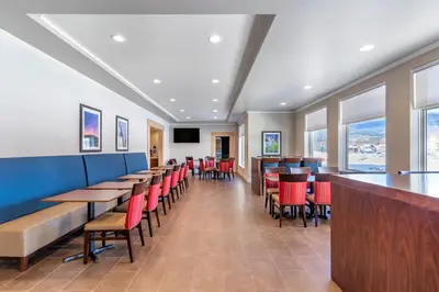 a dining room with tables and red chairs at Comfort Inn & Suites in Valemount