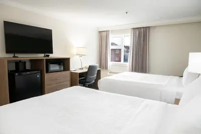 a hotel room with two beds and a flat screen tv at Quality Inn & Suites in Whitehorse