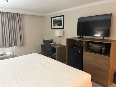 a hotel room with a bed and a flat screen tv at Quality Inn & Suites in Whitehorse