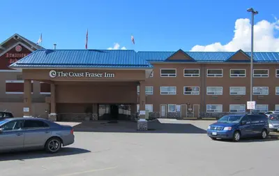two cars parked in a parking lot in front of a building at Coast Fraser Inn in Williams Lake
