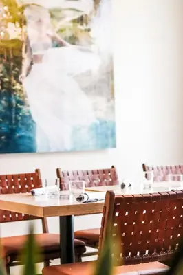 a dining room with tables and chairs and a painting at Seaside Hotel North Vancouver in North Vancouver