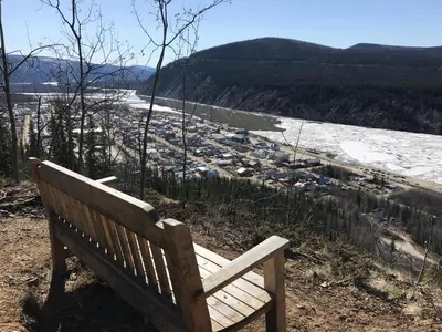 a wooden bench sitting on top of a hill with a view at Dawson Lodge in Dawson City
