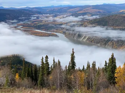 a view of a lake in the mountains with clouds at Dawson Lodge in Dawson City