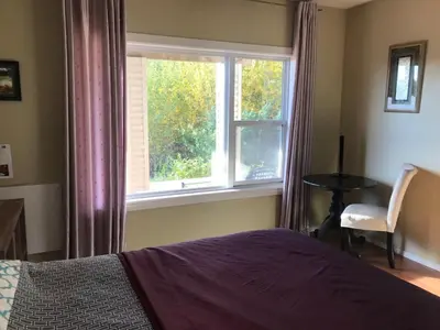 a bedroom with a bed and a window and a chair at 民宿Ann's House in Calgary in Calgary