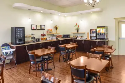 a restaurant with wooden tables and chairs and a counter at Quality Inn & Suites in Whitecourt