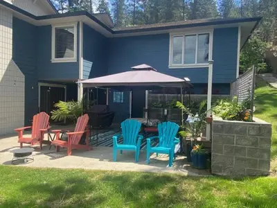 a patio with chairs and an umbrella in front of a house at The Blue House Bed and Breakfast in Lake Country